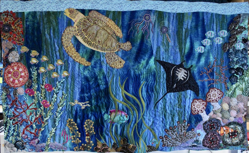 Art quilt "Bounty of the Seas" by Allison Wilbur depicting a coral reef with a sea turtle, fish and coral reef