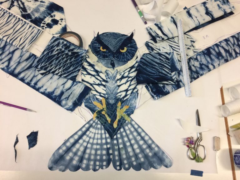 In progress art quilt of owl with fabric being auditioned on the line drawing