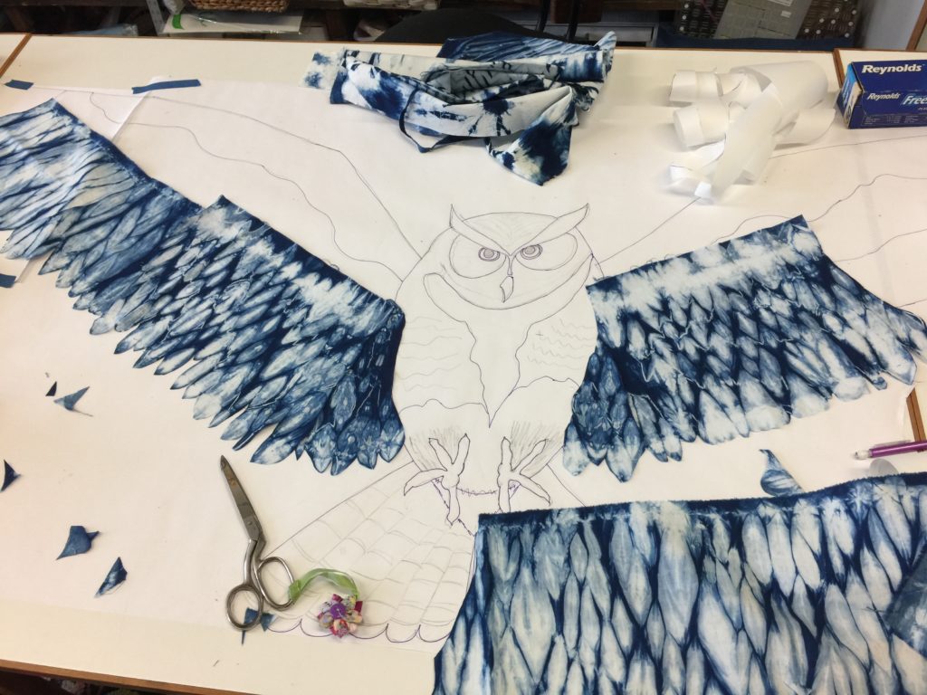 In progress art quilt of owl with fabric being auditioned on the line drawing