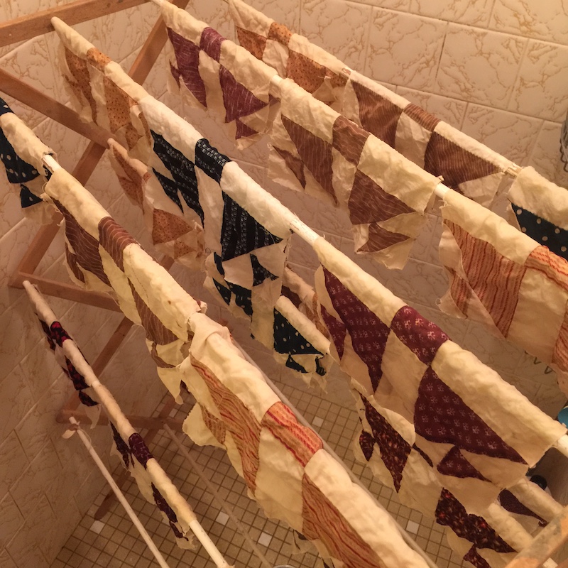 Antique quilt block drying on a wooden rack after being washed.