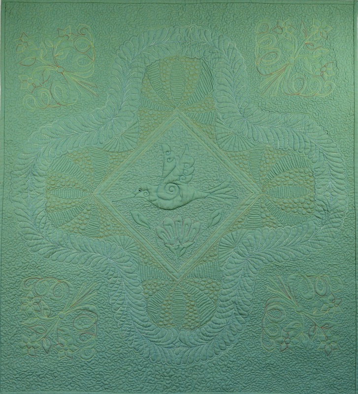 Machine quilted whole cloth quilt with hummingbird in center and feathers and florals all around it