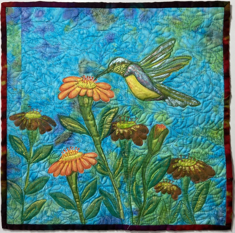 Mini painted art quilt with hummingbird feeding at zinnia flowers