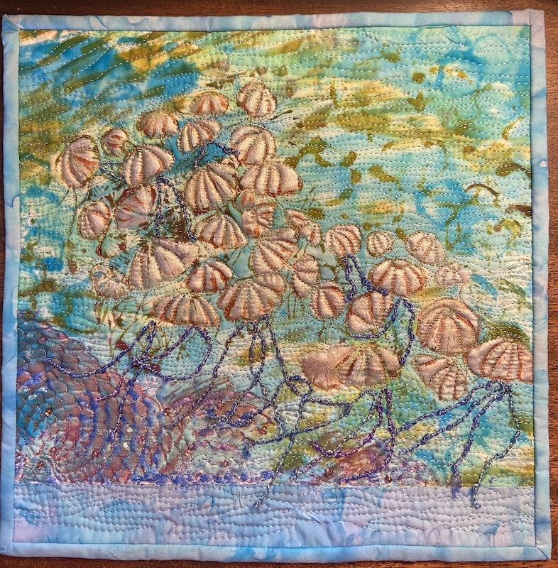 Upwelling, a small art quilt by ALLISON WILBUR depicting a school of jellyfish floating in the water with luminous white bodies and dangling blue tentacles.