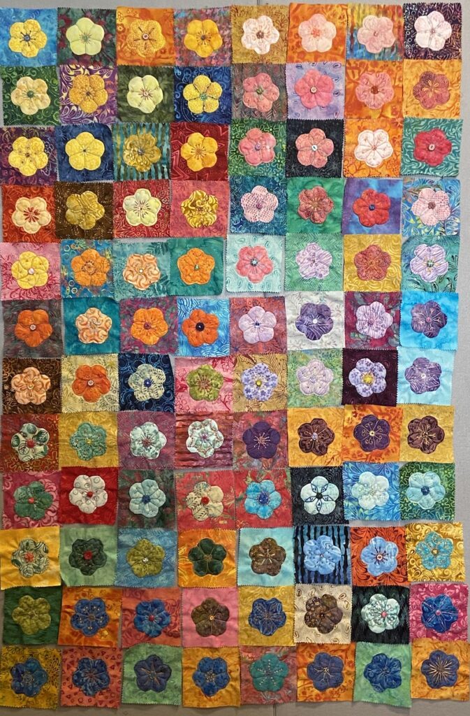 Colorful applique flower quilt blocks on colorful background squares.